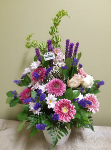Bel arrangement floral funéraire dans les tons de rose et violet