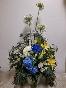 Arrangement floral funéraire dans les tons de blanc, bleu et jaune