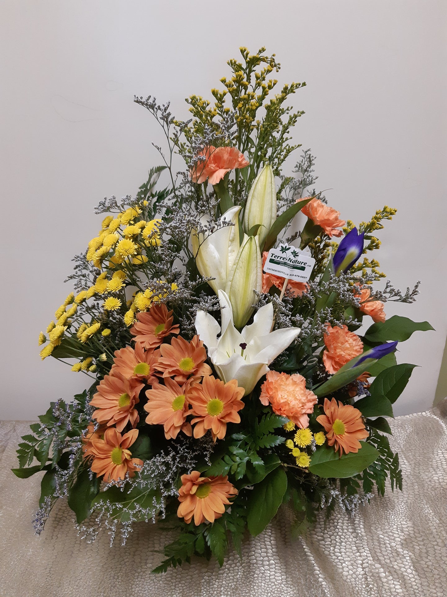 Arrangement floral funéraire dans les tons d'orange, blanc et jaune