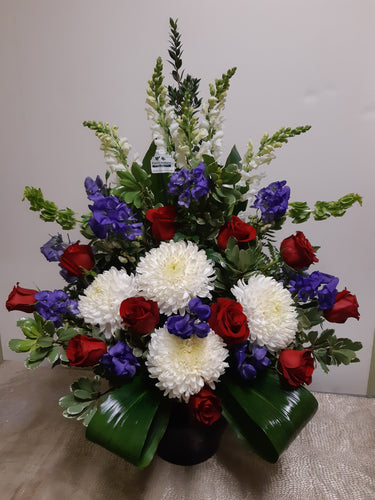 Arrangement floral funéraire dans les tons de rouge, blanc et bleu
