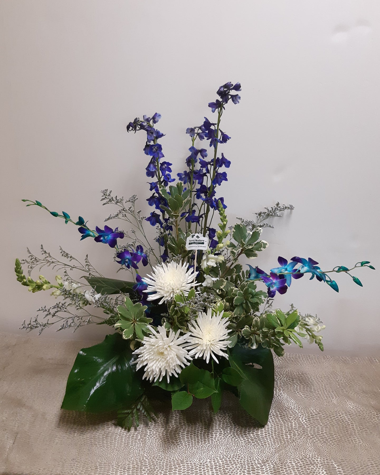 Arrangement floral funéraire élancé dans les tons de blanc et bleu